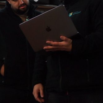 Ein Mann winkt aus einem Monitor mit einer freundlichen Geste.