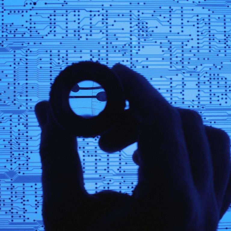 Hand hält einen Ring vor einem blauen, datencodierten Hintergrund.